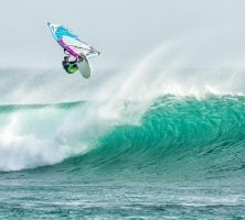 Windsurfer Performing an Aerial Trick Above a Large Turquoise Wave in the Ocean