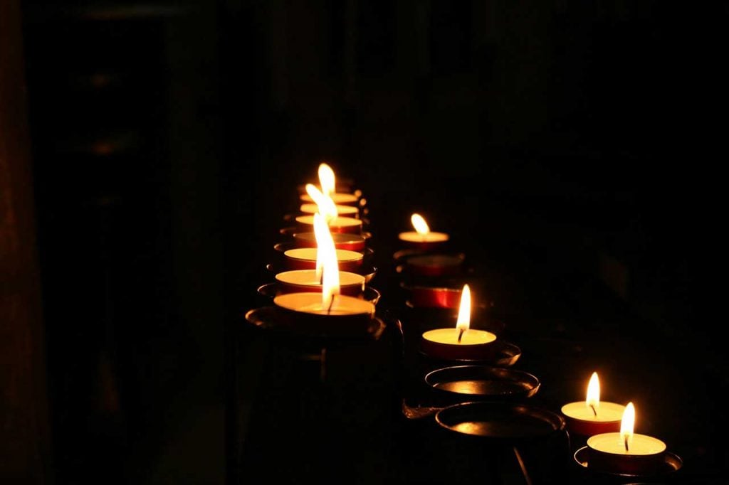 Lit Memorial Candles Glowing In A Dark Funeral Or Cremation Setting