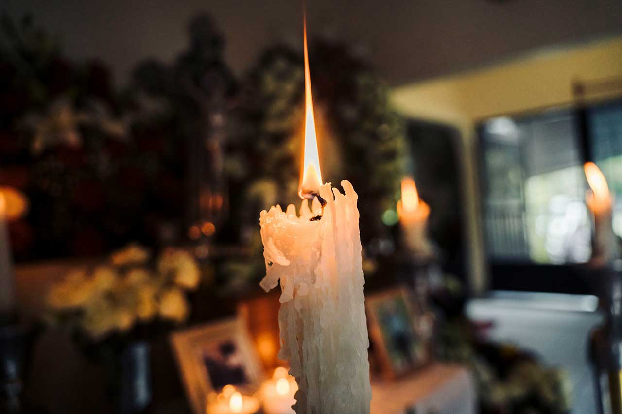 Lit White Memorial Candle With Wax Drippings In A Funeral Or Cremation Setting