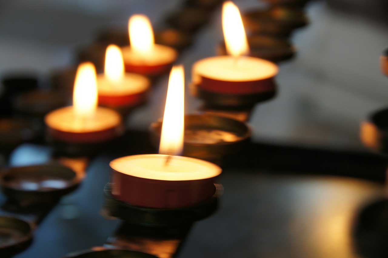 Lit Tea Light Candles Arranged In Rows For A Memorial Or Funeral Setting